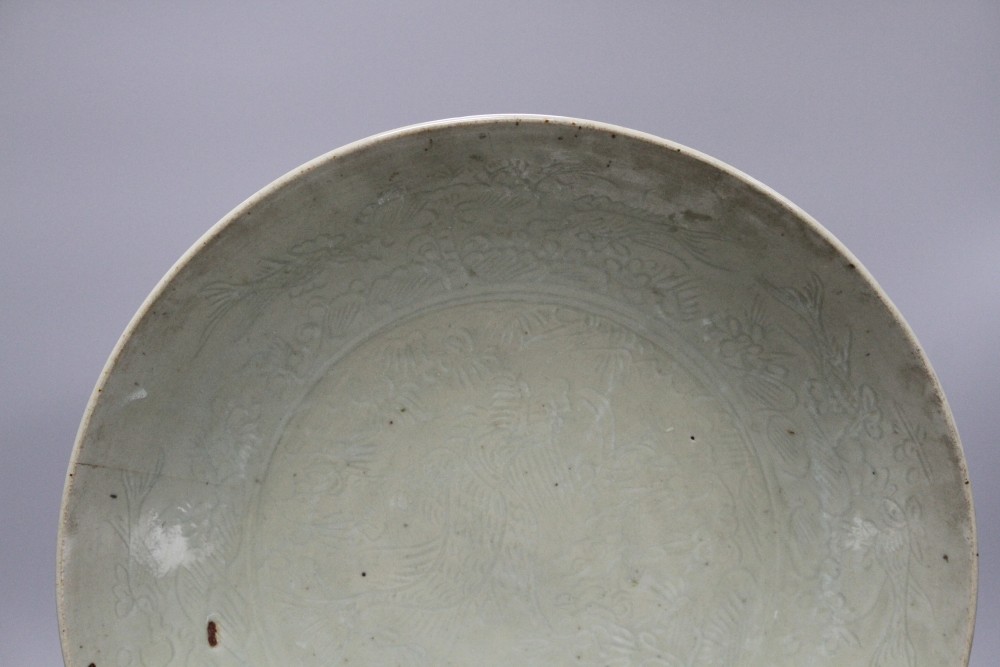 A Chinese Ming celadon dish, Zhangzhou kilns, c.1580-1620, incised with fish and water plants, diameter 38.5cm, height 8cm